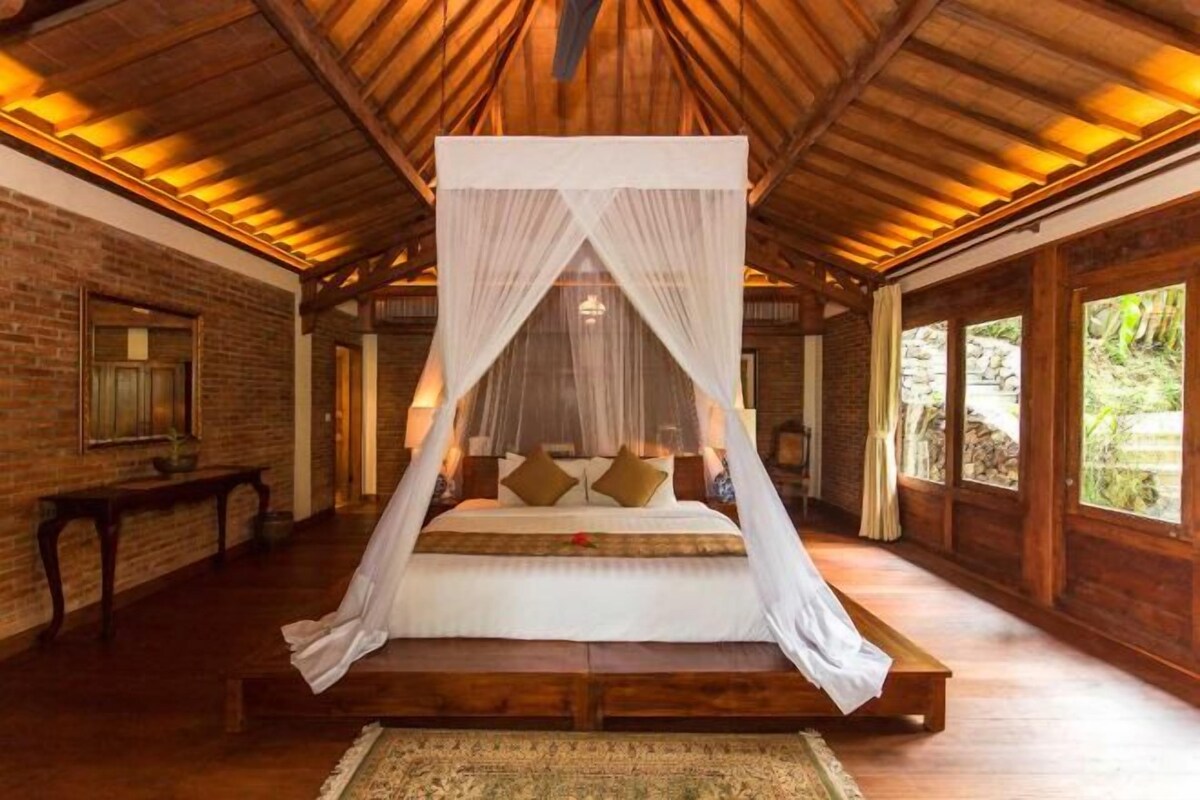 Una cama grande con dosel, paredes de madera y suelo de ladrillo.