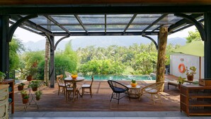 Un área de estar al aire libre cubierta con piscina y abundante vegetación de fondo.