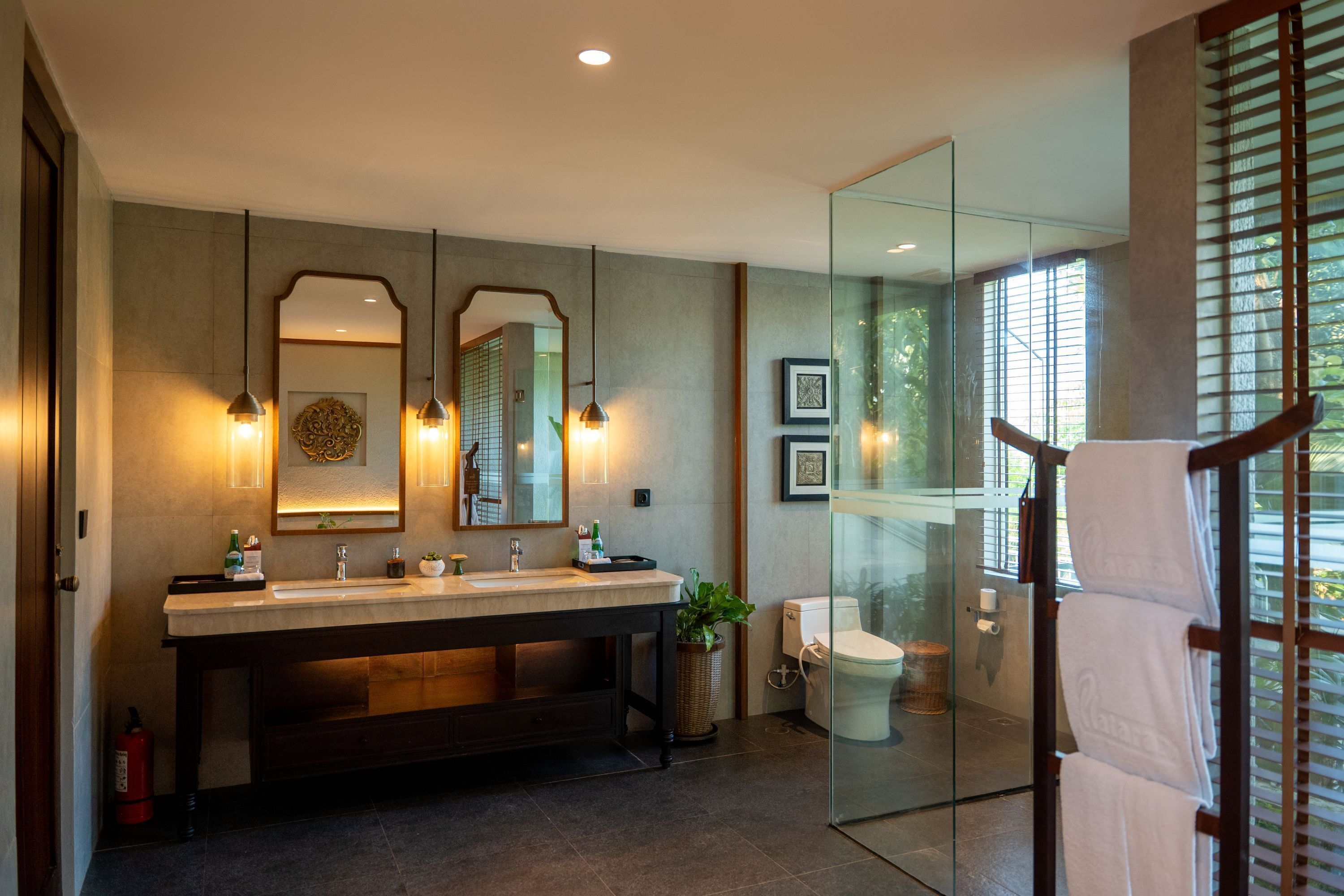 A modern bathroom with a large vanity, two mirrors, a toilet, and a glass shower enclosure.