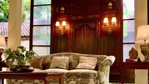 A cozy living room with a patterned sofa, a coffee table, and a decorative lamp. - Rumah Boedi Private Residence Villa (Borobudur)