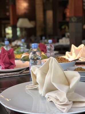 Ein Esstisch mit Tellern voller Essen, Wasserflaschen und Servietten.