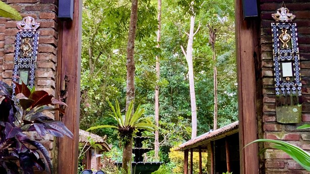 A rustic wooden archway leading to a covered outdoor area with a garden and a fountain. - Rumah Boedi Private Residence Villa (Borobudur)