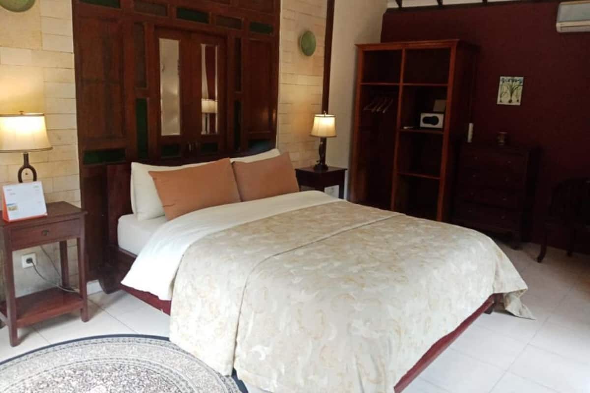 Une chambre à coucher avec un grand lit, une armoire en bois et deux tables de chevet avec des lampes.