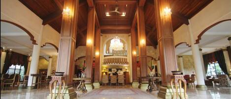 Un vestíbulo amplio con techos altos, candelabros y un mostrador de recepción central.