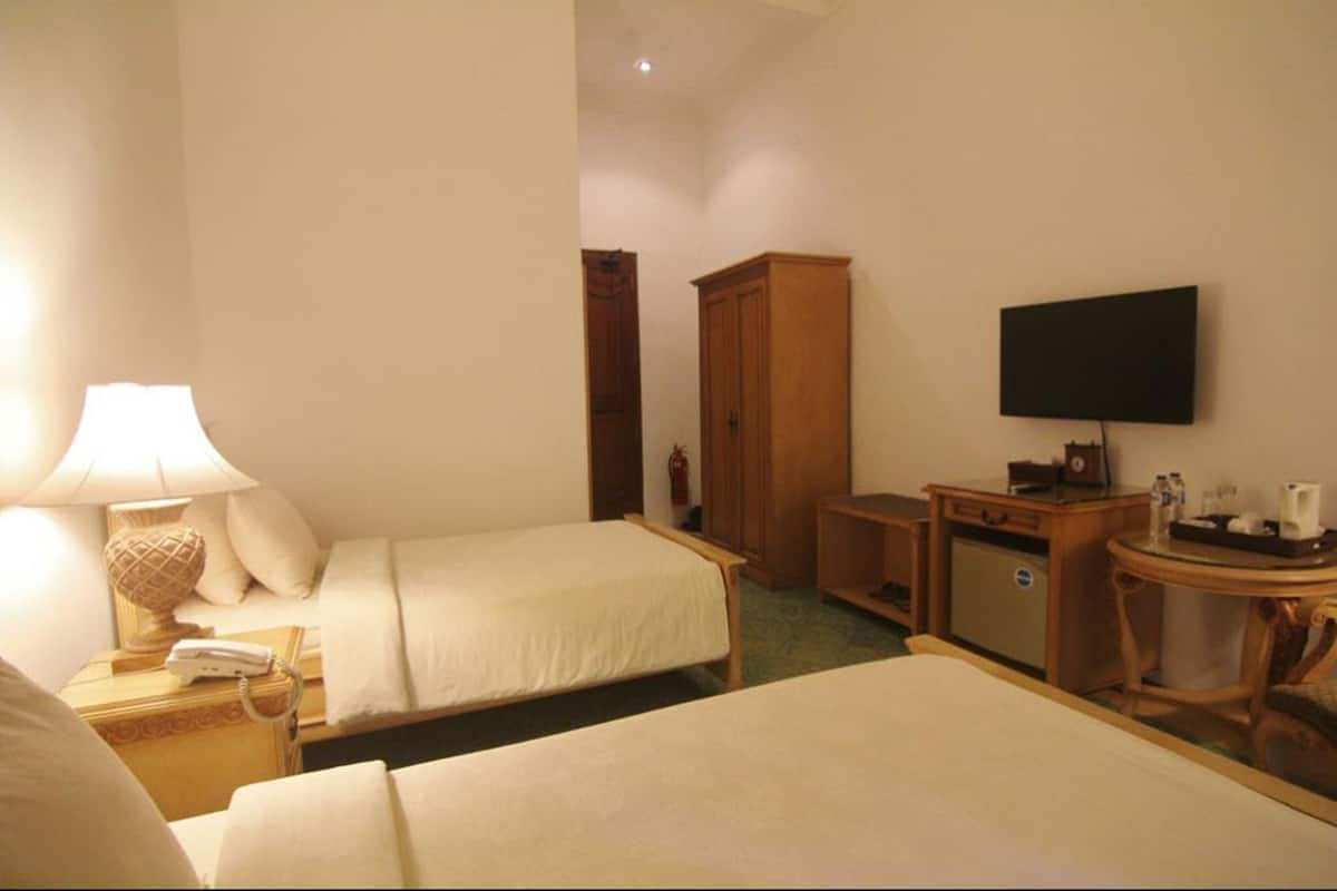 A hotel room with two beds, a desk, a television, and a wardrobe.