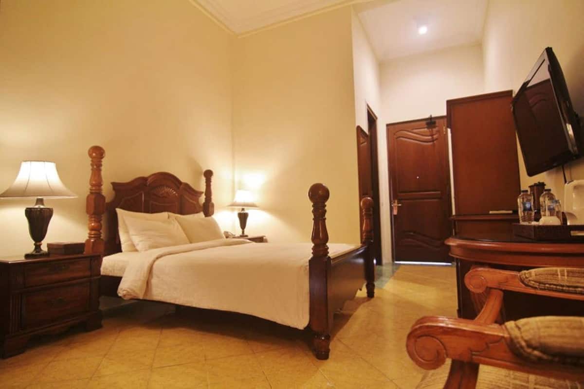 A hotel room with a bed, bedside lamps, a television, and a wooden dresser.