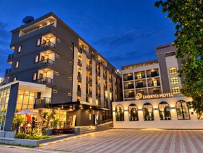 A multi-story hotel with a modern design, featuring balconies and a well-lit entrance. - Embryo Hotel (Pattaya)