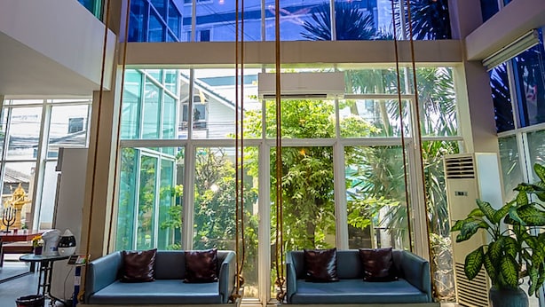 A spacious lobby with a modern chandelier, a blue sofa, and large windows offering a view of the outdoors.