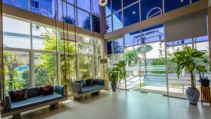 A spacious lobby with large windows, a blue sofa, and potted plants.