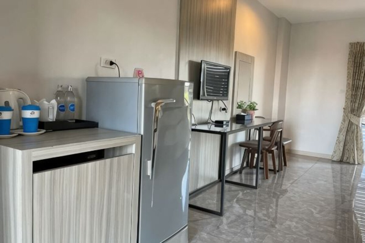 Una cucina compatta con frigorifero, microonde e lavello. C'è una zona pranzo con sedie e tavolo.