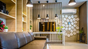 A modern living room with a leather sofa, a TV, and a wall decorated with clocks.