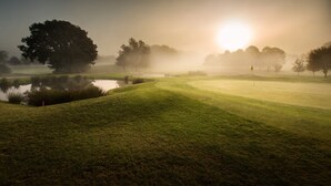 A misty golf course with a pond, trees, and a flag. - Sandford Springs Hotel & Golf Club (Tadley)