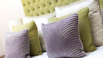 A bed with multiple pillows in various colors and patterns.