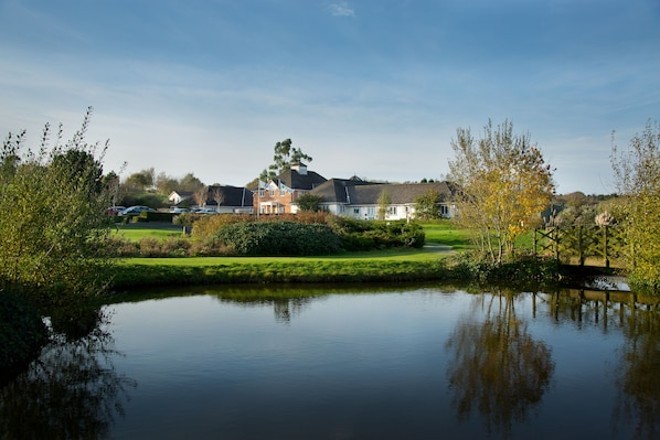 Une vue paisible sur un lac, avec une maison et un pont en arrière-plan.