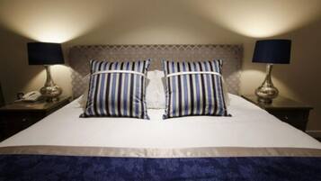 A neatly made bed with striped pillows, a patterned headboard, and two bedside lamps on either side.