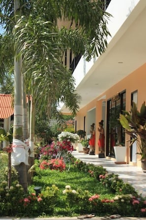 A hotel corridor with a garden area, potted plants, and a statue. - Phuket Airport Inn (Sa Khu)