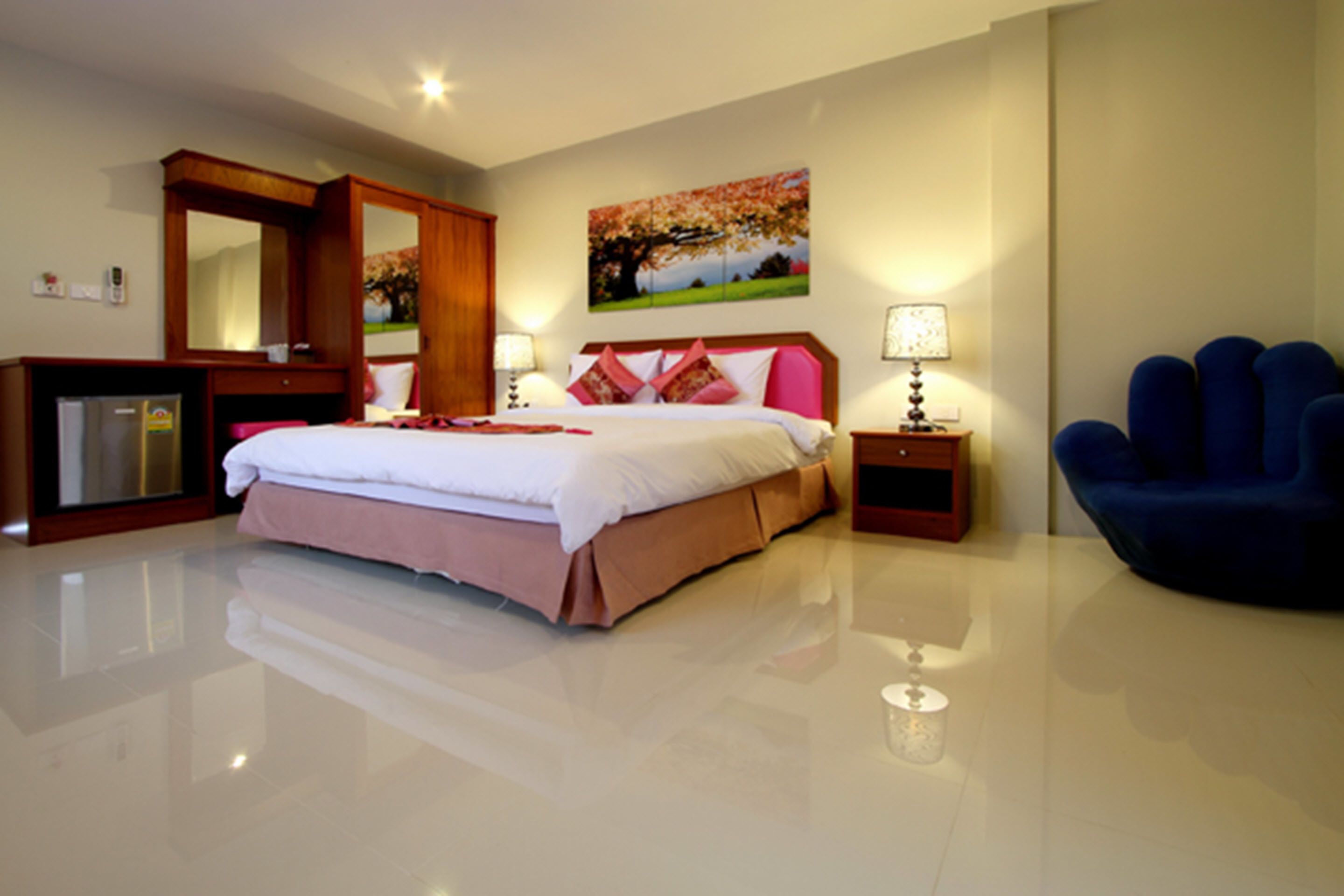 A modern hotel room with a large bed, a desk, a chair, and a painting on the wall.