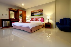 A modern hotel room with a large bed, a desk, a chair, and a painting on the wall. - Phuket Airport Inn (Sa Khu)