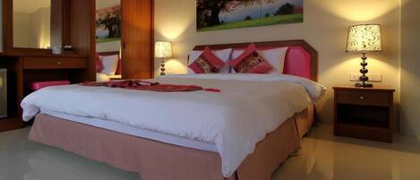 A spacious bedroom with a large bed, a wooden wardrobe, a bedside table with a lamp, and a painting on the wall.