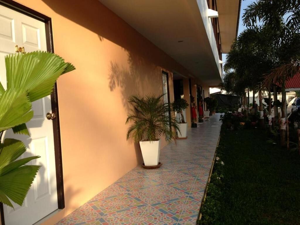Un pasillo de hotel con suelo de baldosas, plantas en macetas y una puerta a la izquierda.