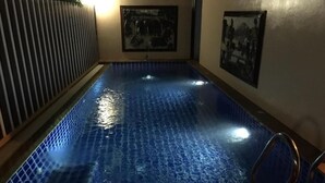A swimming pool with a tiled floor, a wooden deck, and a metal handrail. - Phuket Airport Inn (Sa Khu)