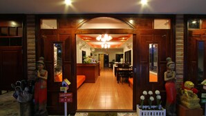 A hotel entrance with a wooden facade, a reception desk, and a dining area visible through the doorway. - Phuket Airport Inn (Sa Khu)