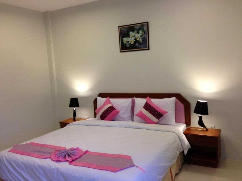 A hotel room with a bed, two bedside tables, a nightstand, a lamp, and a framed picture on the wall.