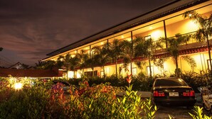 A hotel with a long, flat roof structure, surrounded by lush greenery and a parked car in the foreground. - Phuket Airport Inn (Sa Khu)