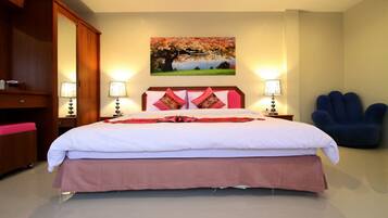 A neatly made bed with a pink skirt, two bedside lamps, and a blue chair.