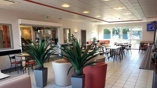 A spacious restaurant with high ceilings, modern furniture, and large windows allowing natural light. - Ace Hôtel Valence  (Valence)