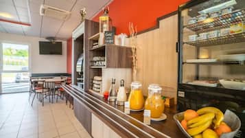 A breakfast bar with juice dispensers, a bowl of fruit, and a coffee station.
