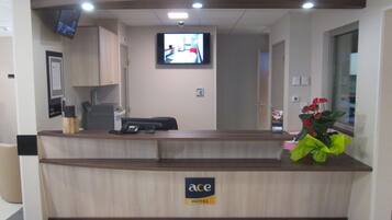 Un mostrador de recepción con un televisor de pantalla plana montado encima, un teléfono y un letrero que indica que pertenece al Ace Hotel.
