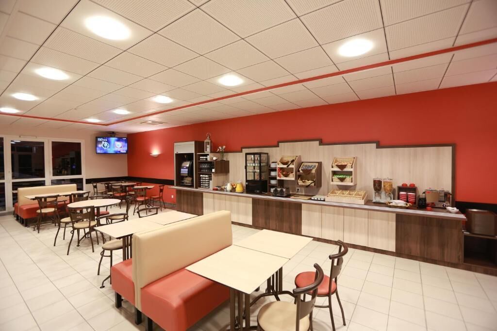 A restaurant with booths and tables, a counter with food displays, and a television screen.