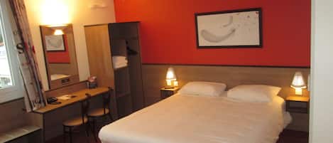 A hotel room with a bed, desk, chair, and two bedside lamps.