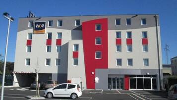 A modern hotel with a prominent red accent wall, multiple windows, and a visible entrance.