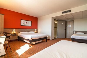Two beds with white bedding, a desk, and a bathroom are featured in this stylish room.