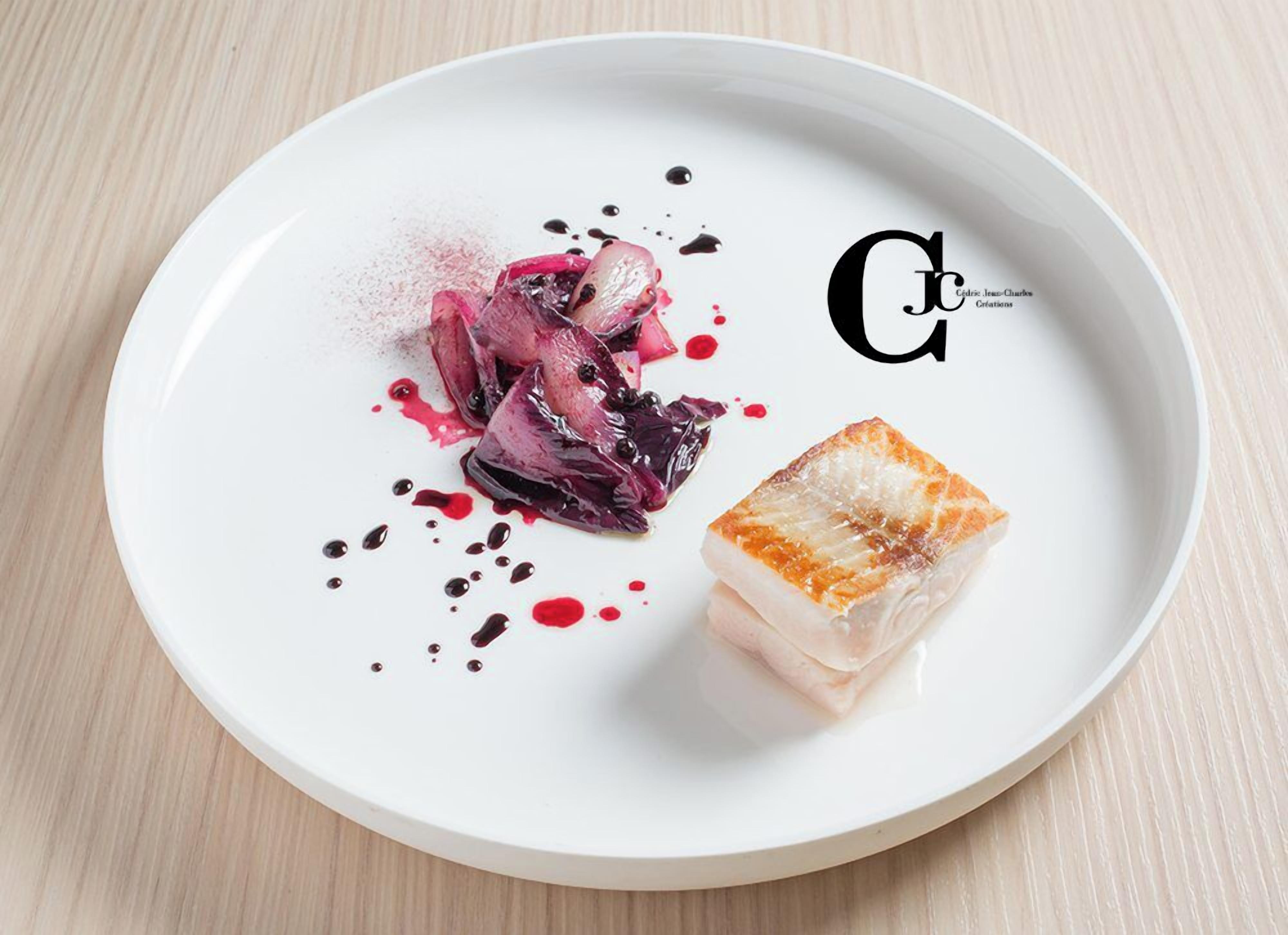 Un plato blanco con un alimento y salsa sobre una mesa de madera.
