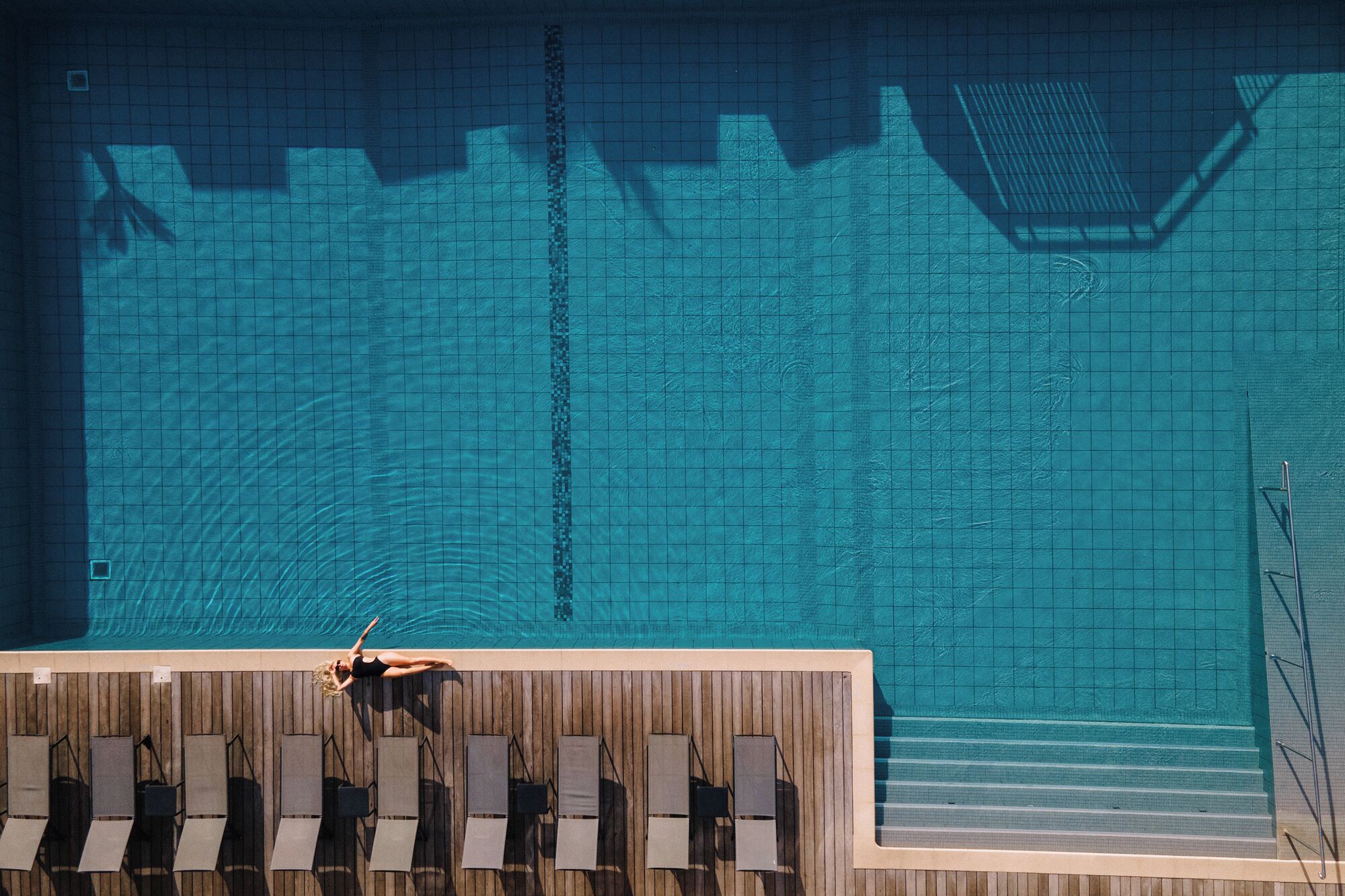 Une piscine dotée d’une terrasse carrelée et de chaises longues.