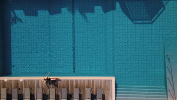 Une piscine dotée d’une terrasse carrelée et de chaises longues.