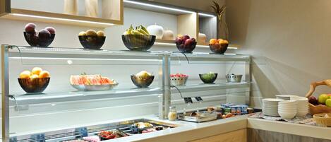 A buffet with various food items and bowls of fruits.
