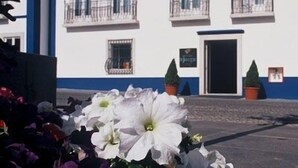 A building with a white facade and blue trim, featuring multiple windows and balconies. - Hotel Jorge Grand (Grandola)