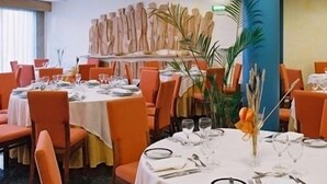 A restaurant with round tables, orange chairs, and white tablecloths. - Hotel Jorge Grand (Grandola)
