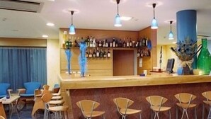 A bar area with a counter, stools, and a variety of bottles. - Hotel Jorge Grand (Grandola)