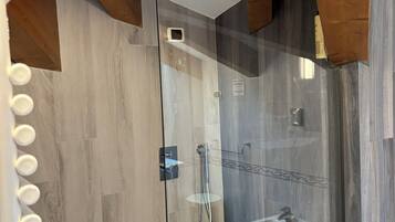 Ein modernes Badezimmer mit Duschkabine aus Glas, Holzbalken und integriertem Waschtisch.
