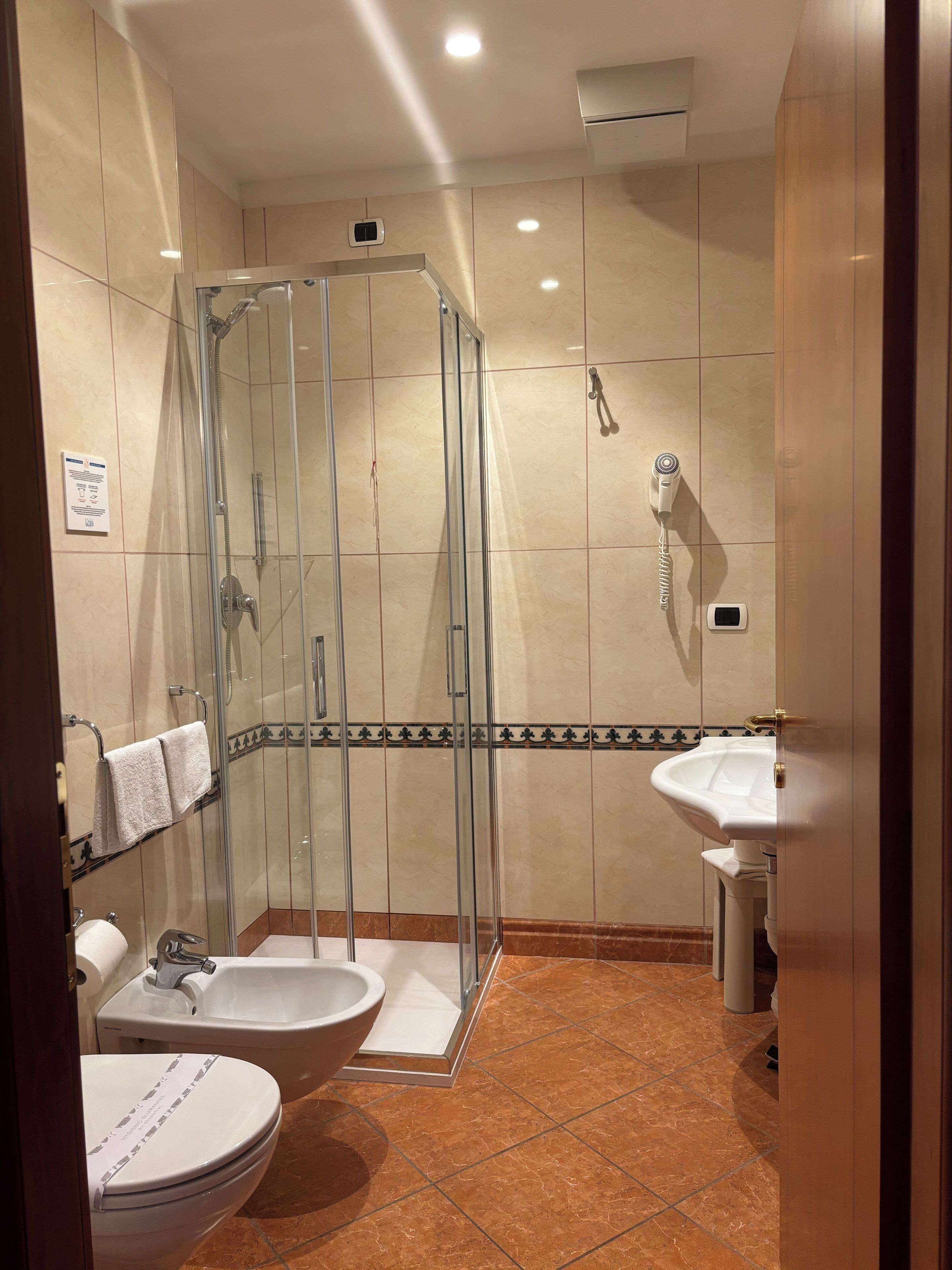 A modern bathroom with a glass-enclosed shower, a sink, and a toilet.
