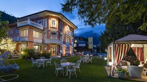 Un hotel grande de varios pisos, con una entrada imponente, zona de estar al aire libre y un porche cubierto.