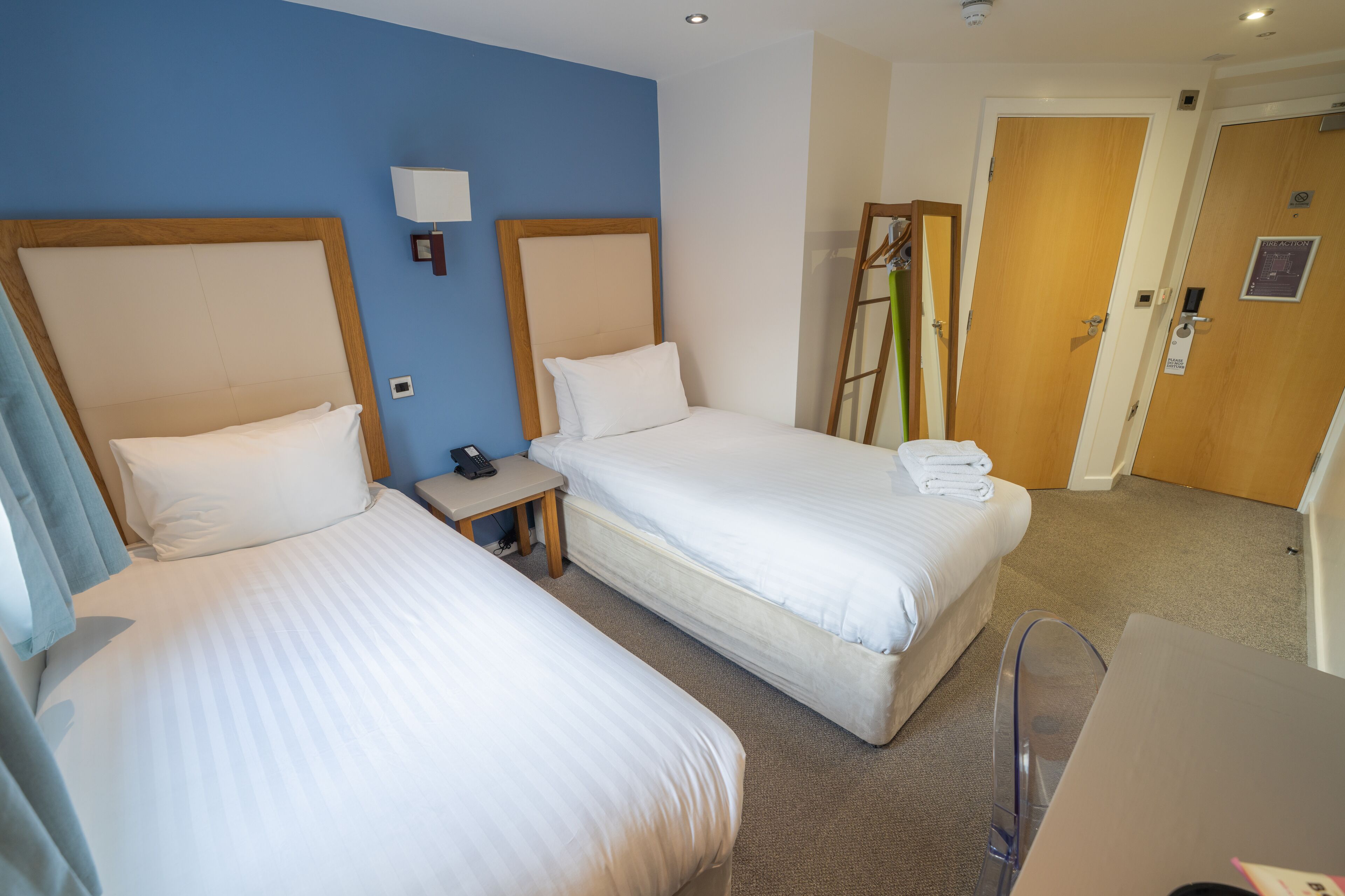 Une chambre d’hôtel avec deux lits, un bureau, une chaise et une armoire.