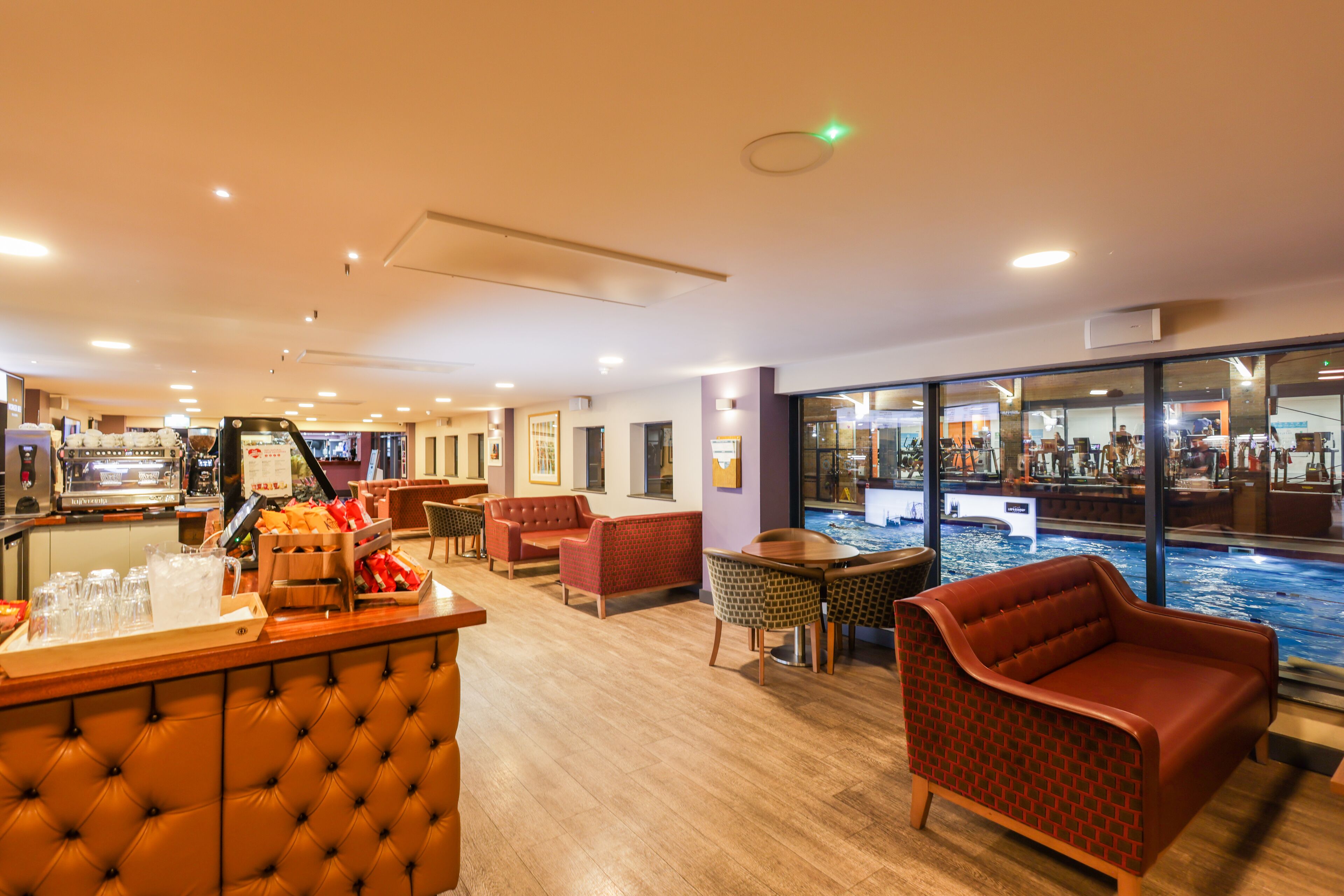 A hotel lobby with a bar area, seating, and a view of an indoor pool.