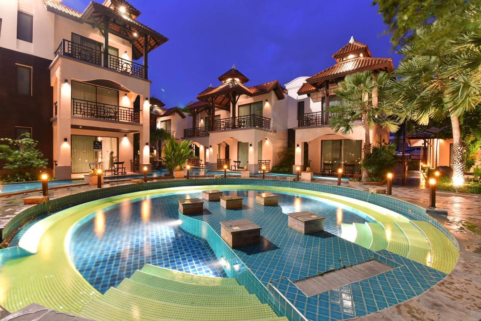 A hotel courtyard with a swimming pool, outdoor seating, and traditional architecture.