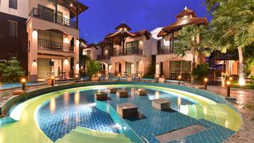 A hotel courtyard with a swimming pool, outdoor seating, and traditional architecture.
